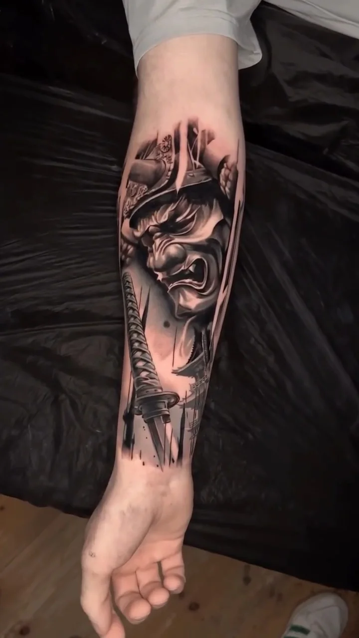the Hannya mask and katana forearm piece revealed from its stencil, black and grey realism tattoo by Lucas Zatti, Temple Bar Dublin